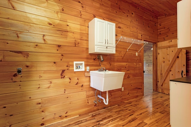 laundry room featuring cabinets, washer hookup, hookup for an electric dryer, wooden walls, and light hardwood / wood-style flooring