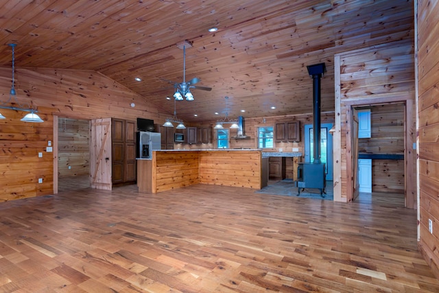 kitchen featuring wooden walls, wall chimney exhaust hood, light hardwood / wood-style floors, and decorative light fixtures