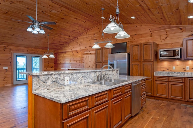 kitchen with wood walls, lofted ceiling, sink, and appliances with stainless steel finishes