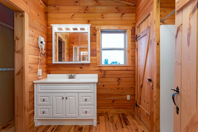 bathroom featuring hardwood / wood-style flooring, vanity, and wood walls