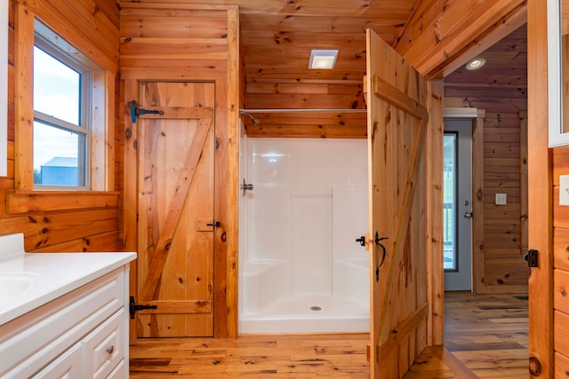 bathroom with hardwood / wood-style floors, vanity, a shower, wooden walls, and wood ceiling