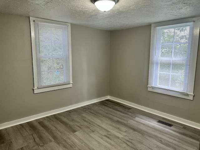 1453 Barnes St NE, Cleveland, TN 37311 - empty room featuring dark wood-type flooring, a textured ceiling, and healthy amount of natural light