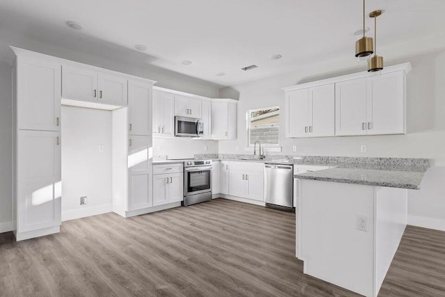 kitchen featuring light stone counters, stainless steel appliances, sink, pendant lighting, and white cabinets