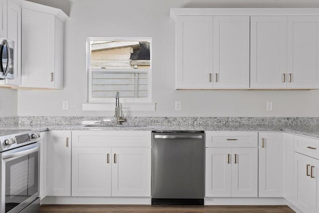 kitchen featuring white cabinets, appliances with stainless steel finishes, light stone counters, and sink