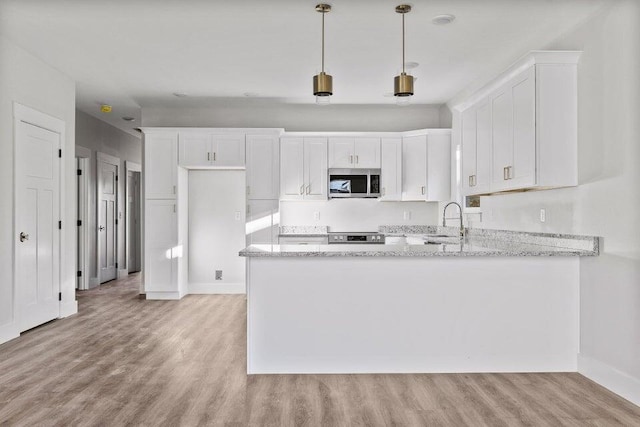 kitchen featuring pendant lighting, sink, white cabinetry, and light stone counters