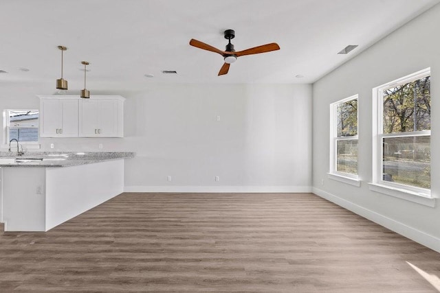 unfurnished living room with ceiling fan, light wood-type flooring, and sink