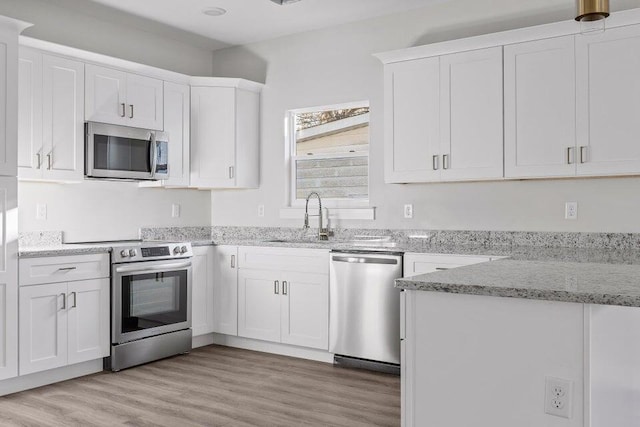 kitchen featuring light stone counters, white cabinets, and stainless steel appliances