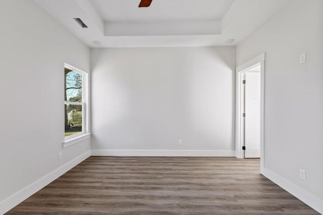 spare room featuring a tray ceiling, ceiling fan, and dark hardwood / wood-style floors