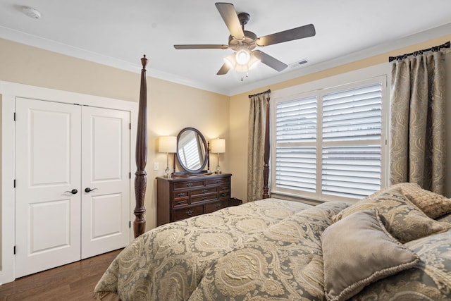 bedroom with crown molding, dark wood-type flooring, a closet, and ceiling fan