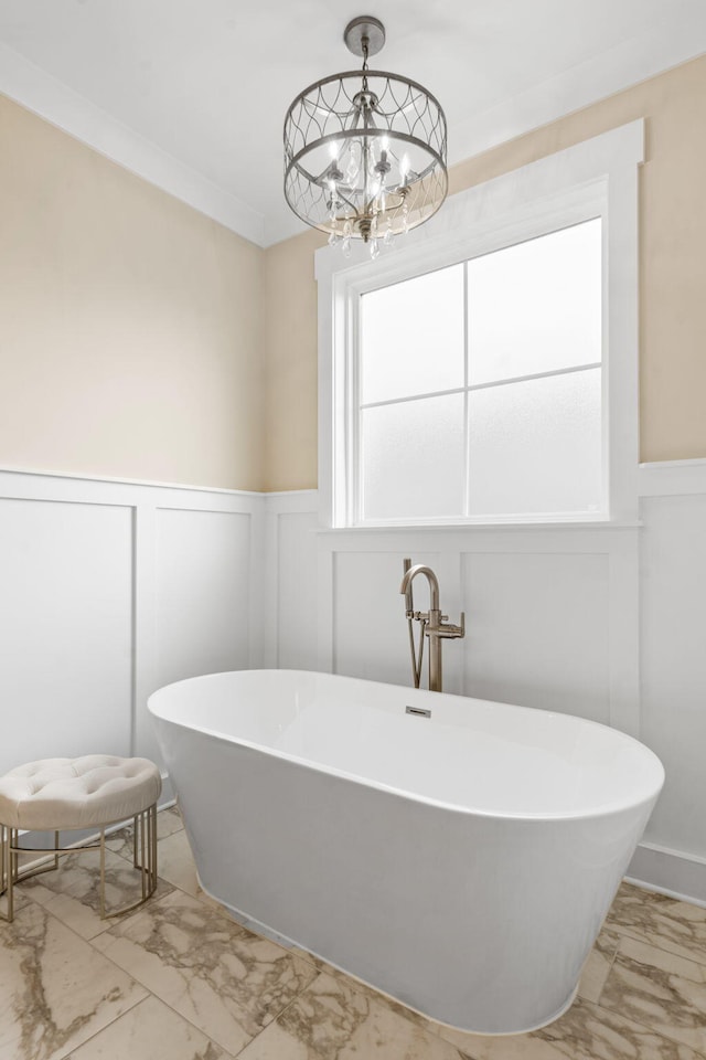 bathroom with a notable chandelier, a bathtub, and ornamental molding