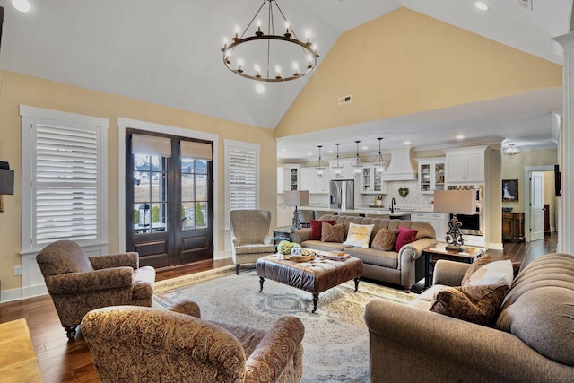 living room featuring french doors, sink, wood-type flooring, high vaulted ceiling, and a notable chandelier