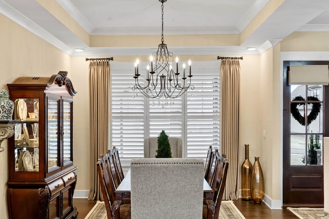 dining area with dark wood-type flooring, a healthy amount of sunlight, a raised ceiling, and a notable chandelier