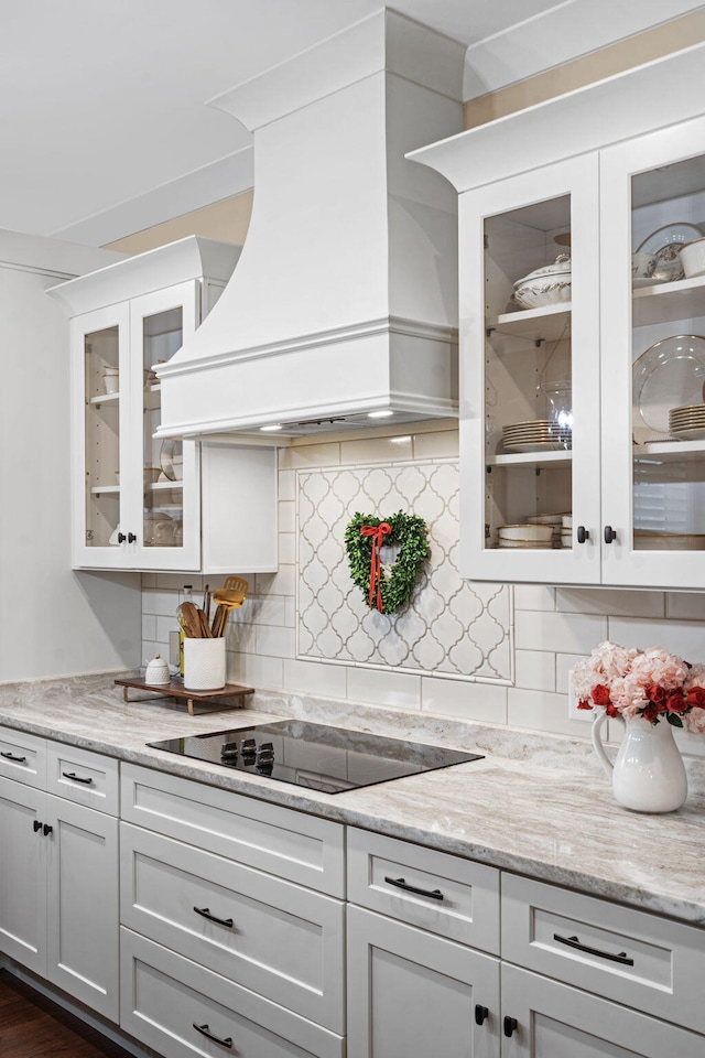 kitchen featuring premium range hood, white cabinetry, black electric cooktop, and light stone counters