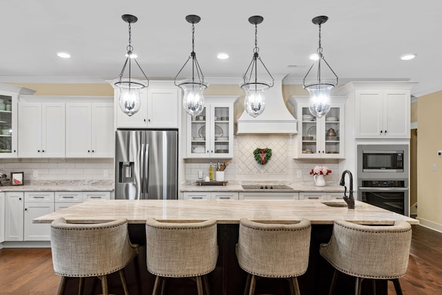 kitchen with white cabinetry, sink, stainless steel appliances, and an island with sink