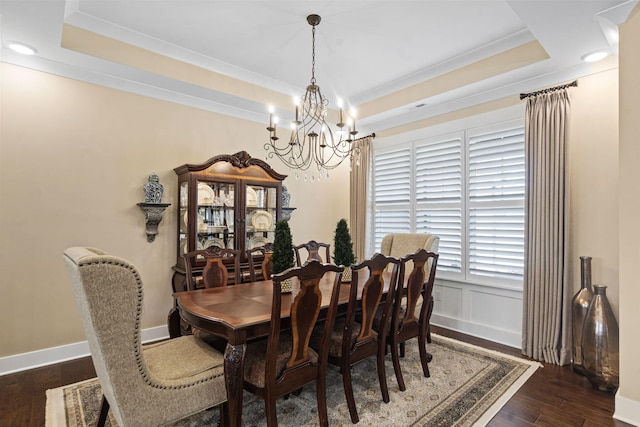 dining space featuring dark hardwood / wood-style flooring, a notable chandelier, crown molding, and a raised ceiling