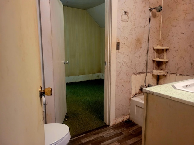 bathroom with hardwood / wood-style floors, vanity, vaulted ceiling, and toilet