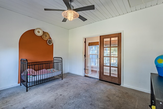 carpeted bedroom featuring a crib and ceiling fan