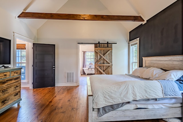 bedroom with beamed ceiling, a barn door, hardwood / wood-style floors, and high vaulted ceiling