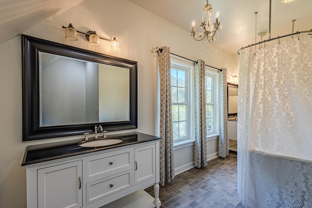 bathroom with an inviting chandelier, lofted ceiling, and vanity