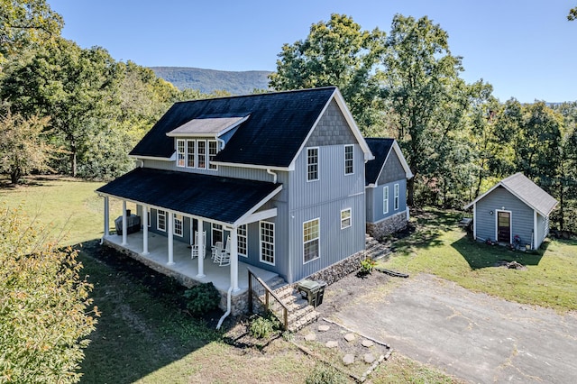 view of front of house featuring a mountain view, an outbuilding, a front yard, and a patio area