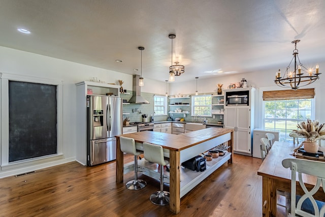 kitchen featuring island exhaust hood, wood-type flooring, stainless steel fridge, and decorative light fixtures