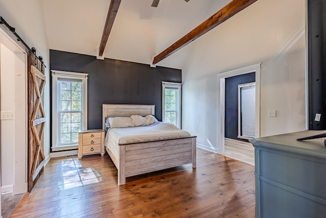 bedroom with dark hardwood / wood-style floors, lofted ceiling with beams, a barn door, and ceiling fan