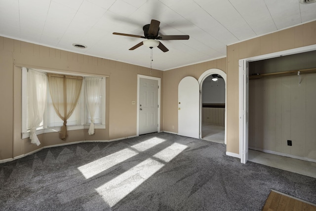 unfurnished bedroom with carpet floors, ceiling fan, and wood walls