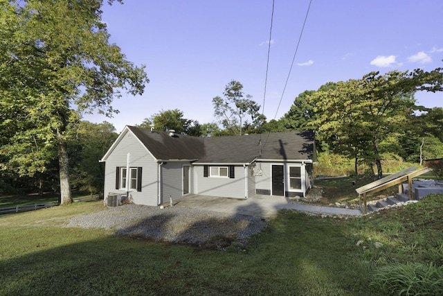 rear view of property featuring a patio, central AC, and a lawn