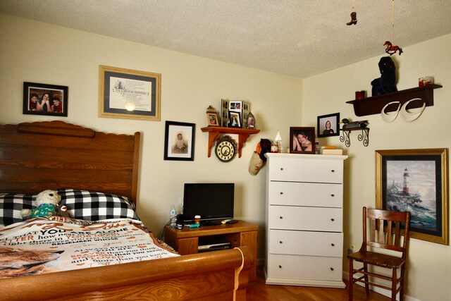 bedroom with a textured ceiling and hardwood / wood-style floors