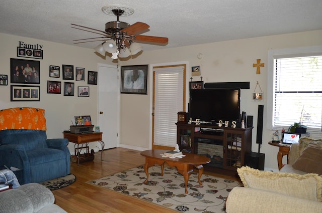 living room featuring ceiling fan, a textured ceiling, and hardwood / wood-style flooring