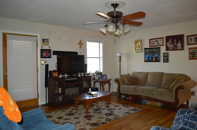 living room with ceiling fan, a textured ceiling, and hardwood / wood-style flooring