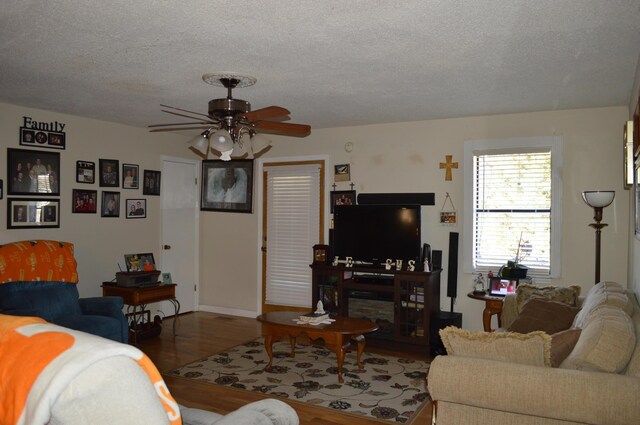 living room with a textured ceiling, ceiling fan, and wood-type flooring