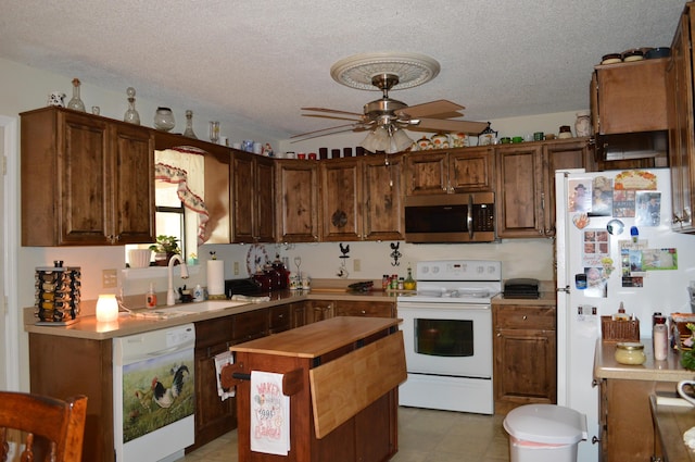 kitchen featuring ceiling fan, sink, white appliances, and a textured ceiling