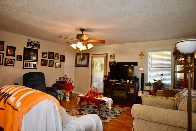 living room with ceiling fan, hardwood / wood-style floors, and a textured ceiling