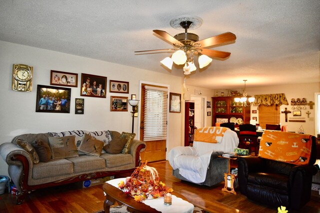 living room featuring ceiling fan with notable chandelier, a textured ceiling, and dark hardwood / wood-style flooring