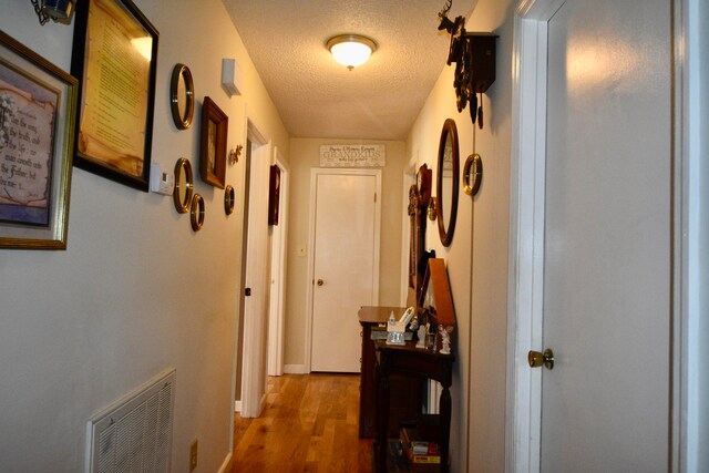 hallway with wood-type flooring and a textured ceiling