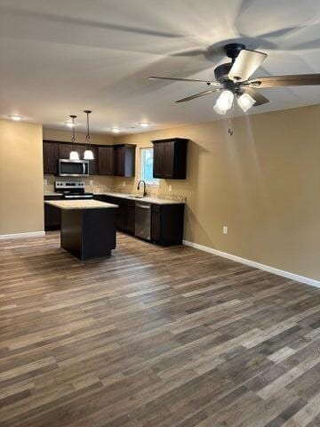 kitchen with sink, appliances with stainless steel finishes, a kitchen island, dark hardwood / wood-style flooring, and decorative light fixtures