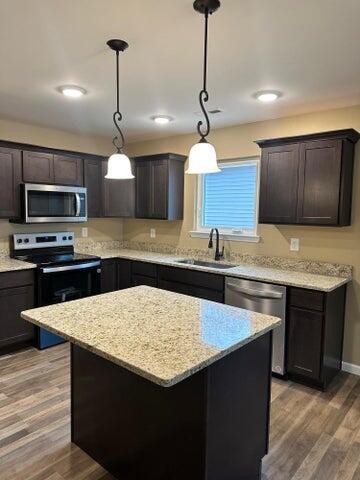 kitchen featuring decorative light fixtures, sink, a center island, stainless steel appliances, and dark brown cabinets