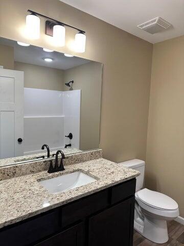 bathroom featuring walk in shower, vanity, toilet, and hardwood / wood-style floors