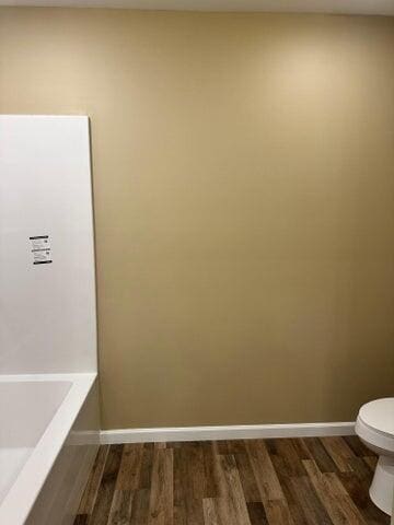 bathroom featuring hardwood / wood-style flooring, a tub, and toilet