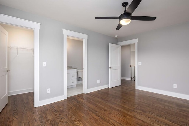 unfurnished bedroom with connected bathroom, dark hardwood / wood-style flooring, a walk in closet, ceiling fan, and a closet