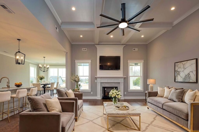 living room featuring beamed ceiling, a healthy amount of sunlight, a high end fireplace, and light wood-type flooring