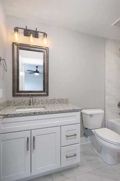 full bathroom featuring tiled shower / bath combo, vanity, and toilet