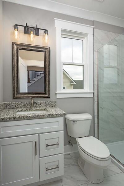 bathroom with vanity, a shower with shower door, and toilet