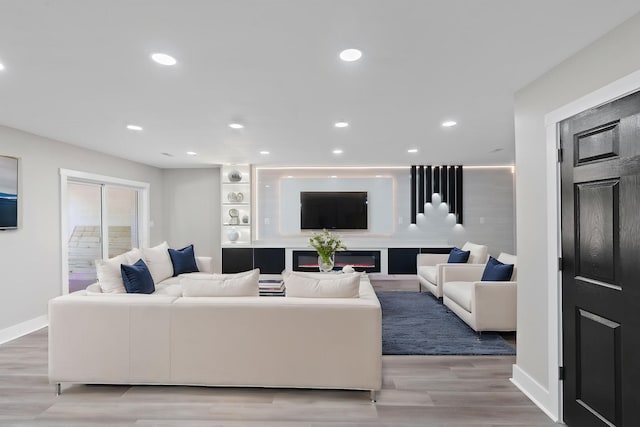 living area with recessed lighting, baseboards, and light wood-type flooring