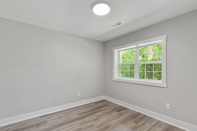empty room with baseboards, wood finished floors, and visible vents
