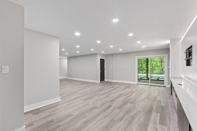 unfurnished living room with recessed lighting, baseboards, and light wood-style flooring