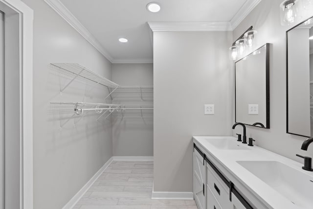 bathroom with a sink, baseboards, ornamental molding, and recessed lighting