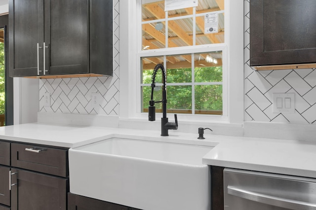 kitchen with a sink, light countertops, decorative backsplash, and dishwasher