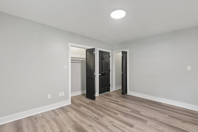 unfurnished bedroom featuring light wood-style floors, baseboards, and a closet